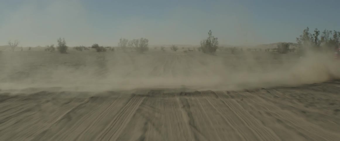 Car speeding in a dirt and brush covered field