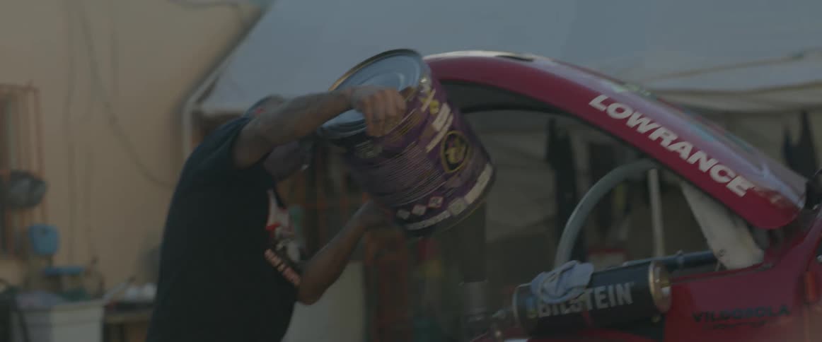 A man pours fluid into a race car engine