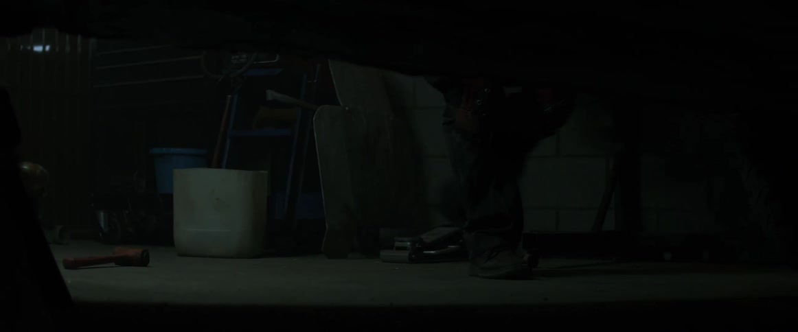 A man is seen walking past the car in the dark room