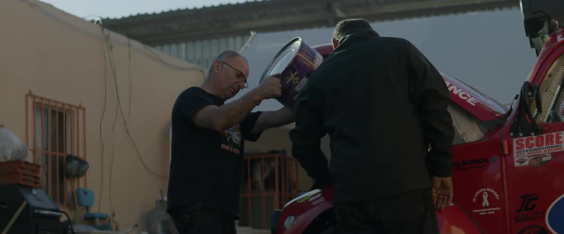 A man is pouring a huge can into an engine