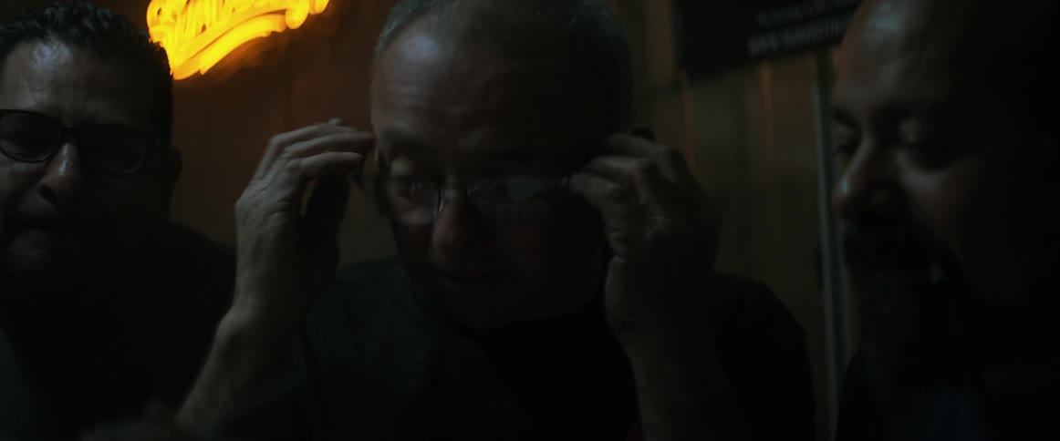 Man talks as he puts on his glasses