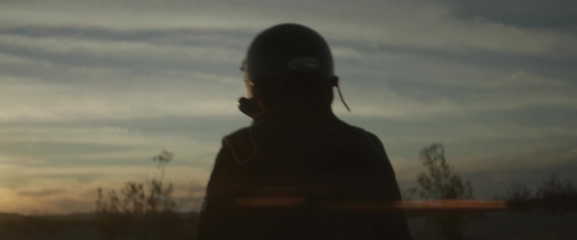 A person with a helmet is walking in the desert