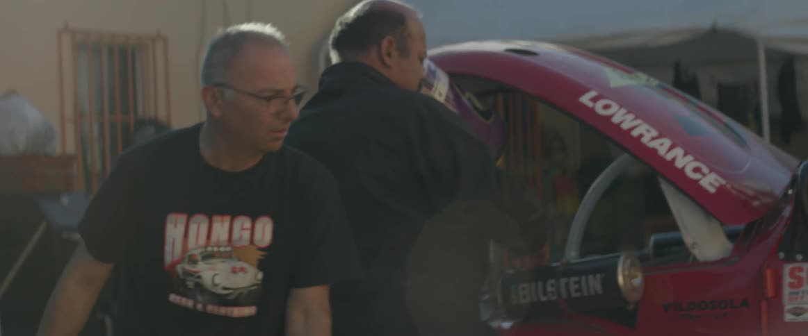 People walk around a car working on it