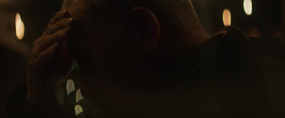 A man rubs his forehead outside at night