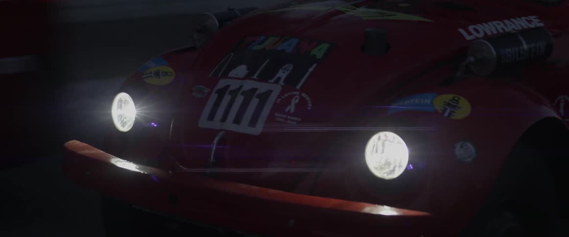 A car is driving shining it's headlights at night