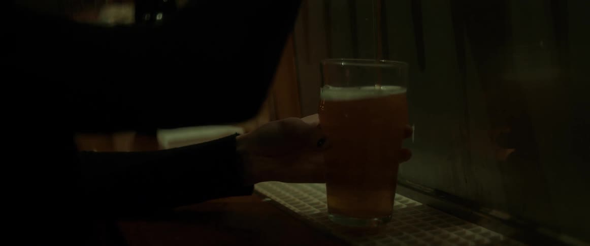 A person pours beer into a glass from a still