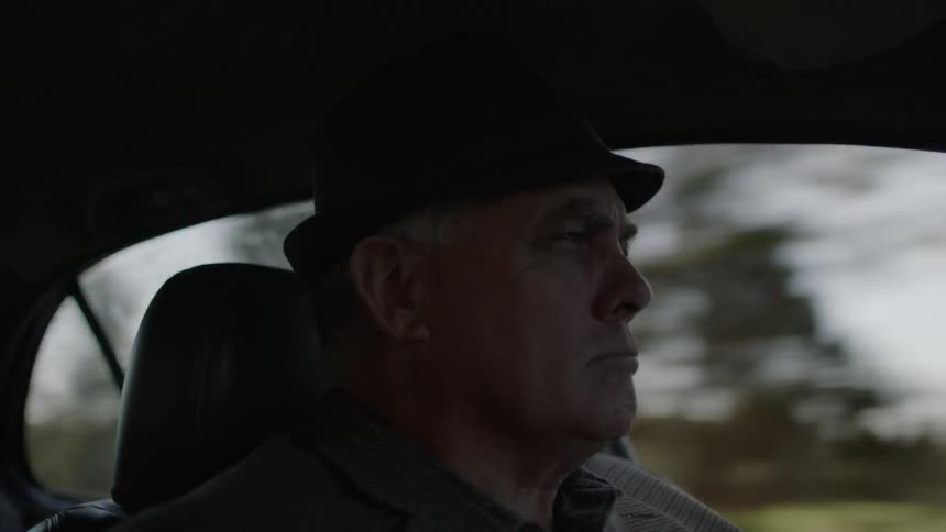 An older man is driving a vehicle during the day