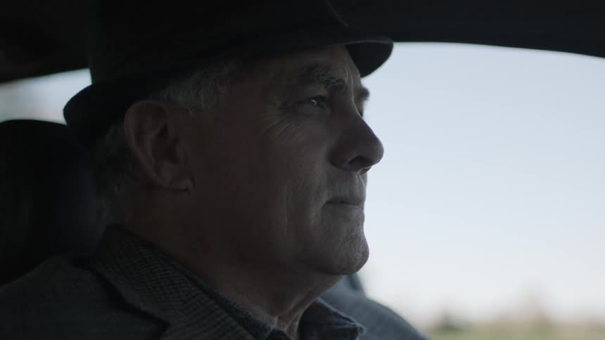 A man in a gray hat drives