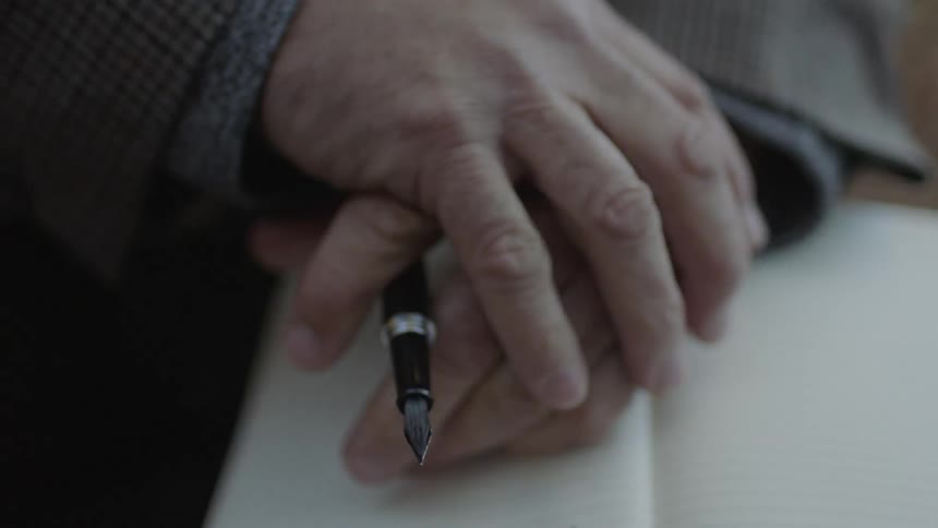 A man writes in a notebook with a pen