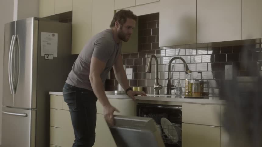 Man puts a cup into the dishwasher