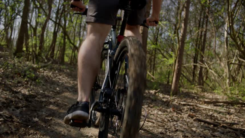 A man is riding an off-road bicycle on a dirt path in a natural setting