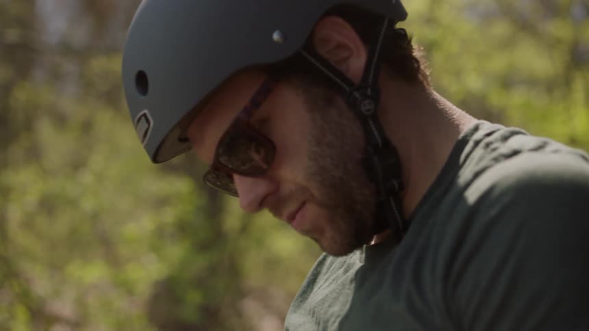 A man wearing a biking helmet is stopped and concentrating on something
