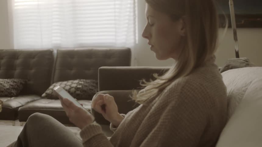 Woman using her smartphone while sitting on a couch