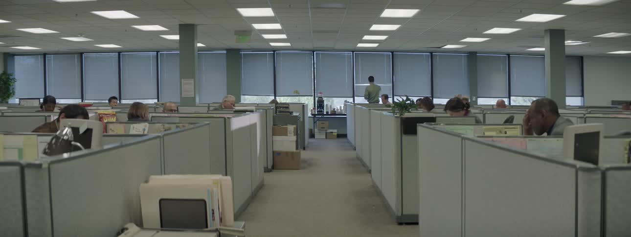 A few people working in an office setting with cubicles