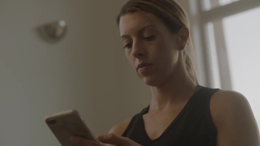 A woman is checking her cell phone while standing inside