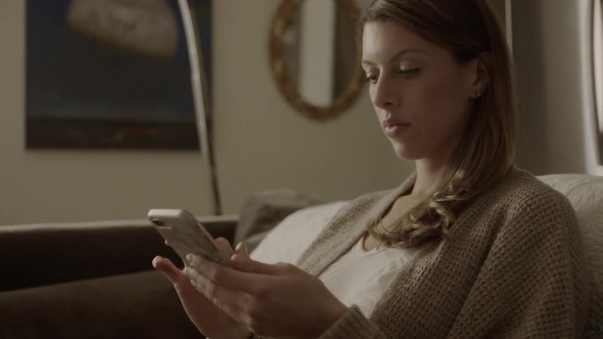 A woman uses a smartphone while sitting on a couch