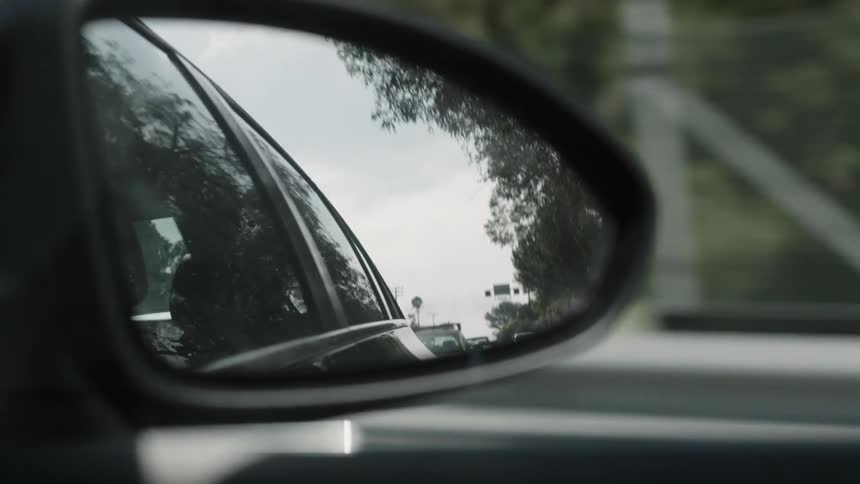 The passing street reflected in a side view mirror