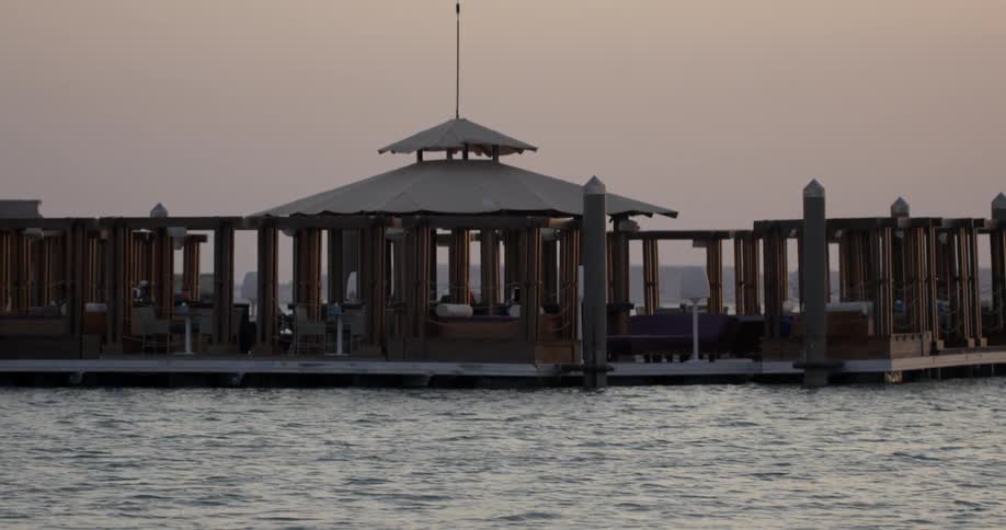 Ocean water flows around a pier with gazebos