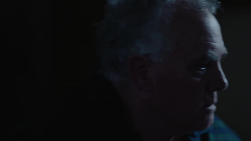 An older man sits up in his bed