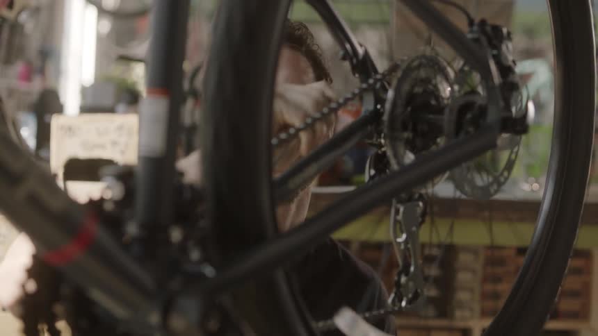 A man tightens a spinning bicycle tire