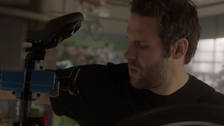 A man spins a bicycle tire in a bike shop