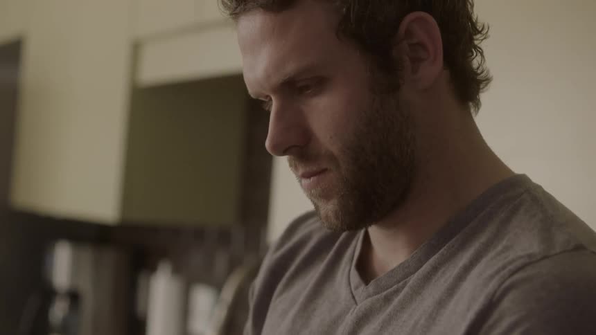 A man texts on his phone in the kitchen