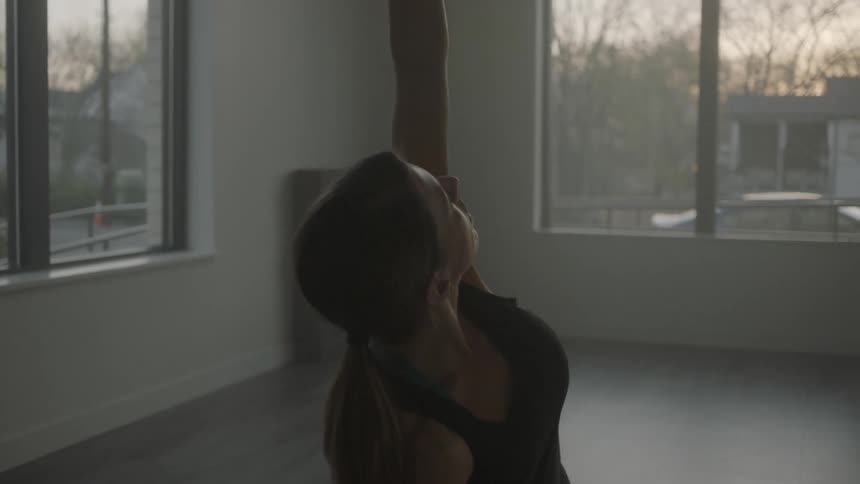 A woman is doing yoga poses in a room in the morning