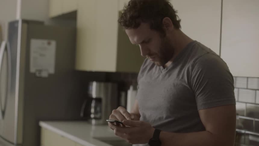 A man uses a smartphone in a kitchen