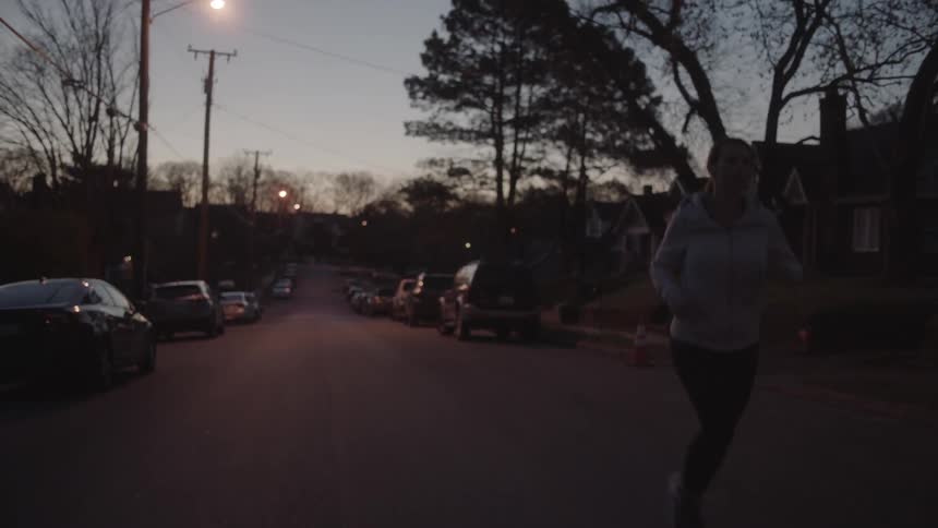 A woman jogs on a residential street at sunset