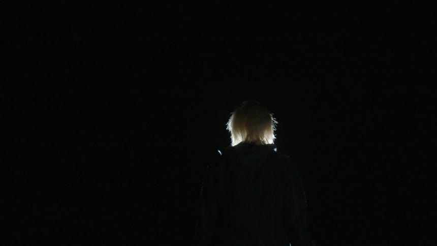 A light illuminates a person's head outside in pitch black