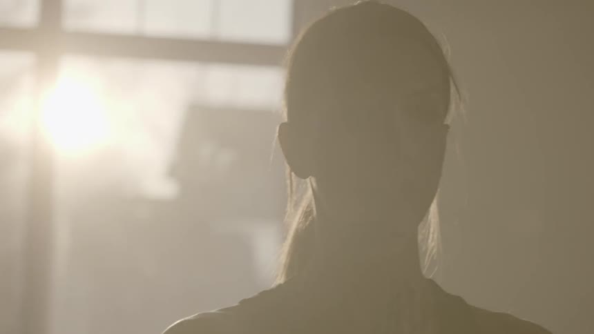 A woman does yoga in front of a sunny window