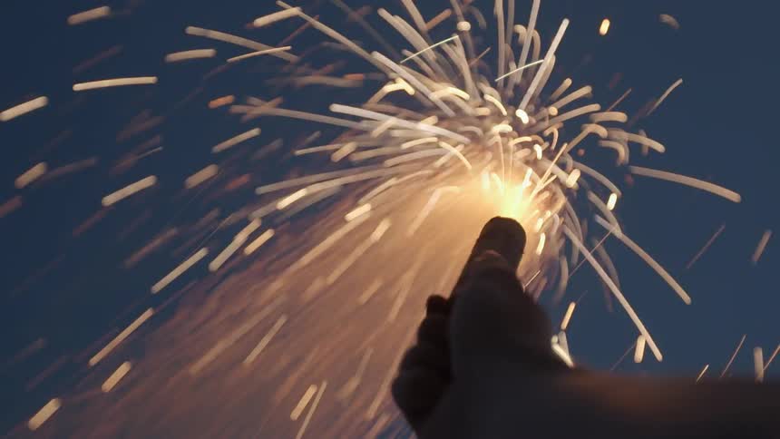 A person is holding a burning flare up towards the sky