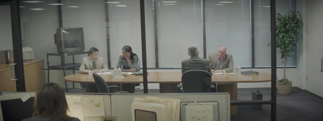 Four people sit at a table in a meeting room