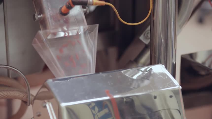 Pills or pellets fall through a funnel in a machine
