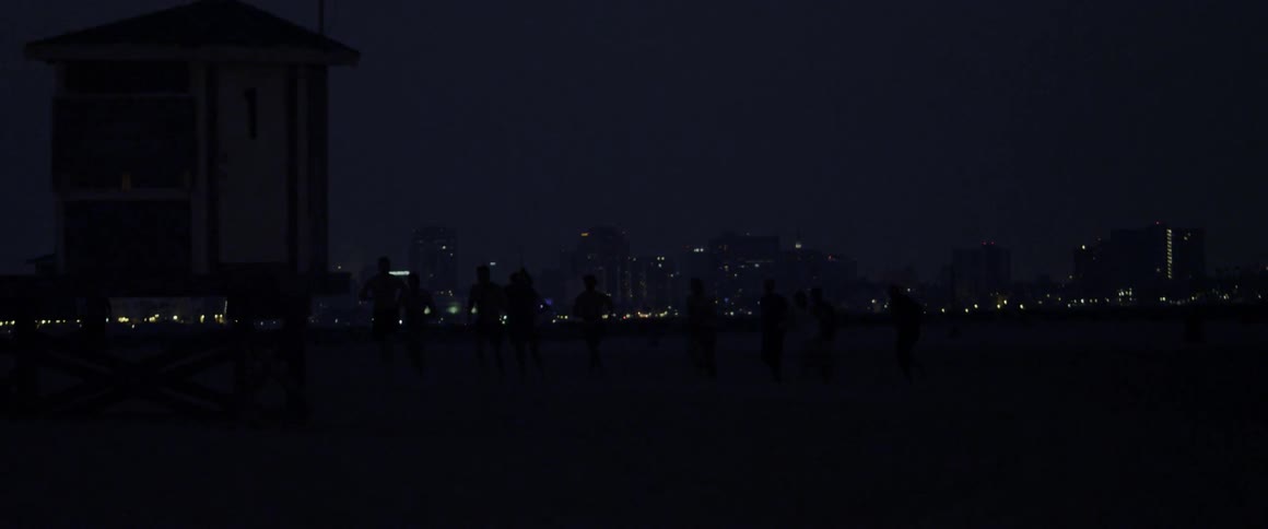 People walking towards some city lights on a clear night