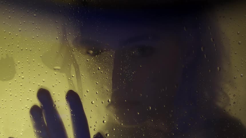 Person presses hand down a wet window