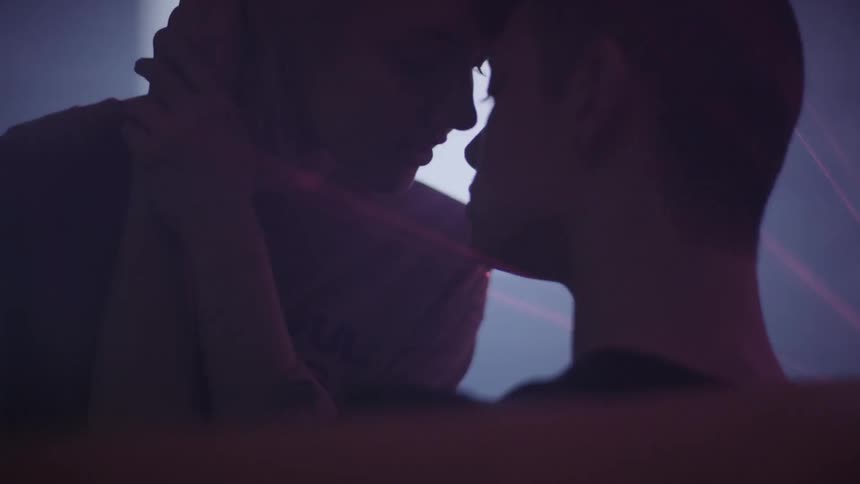 A man and woman kiss with lights shining all around them