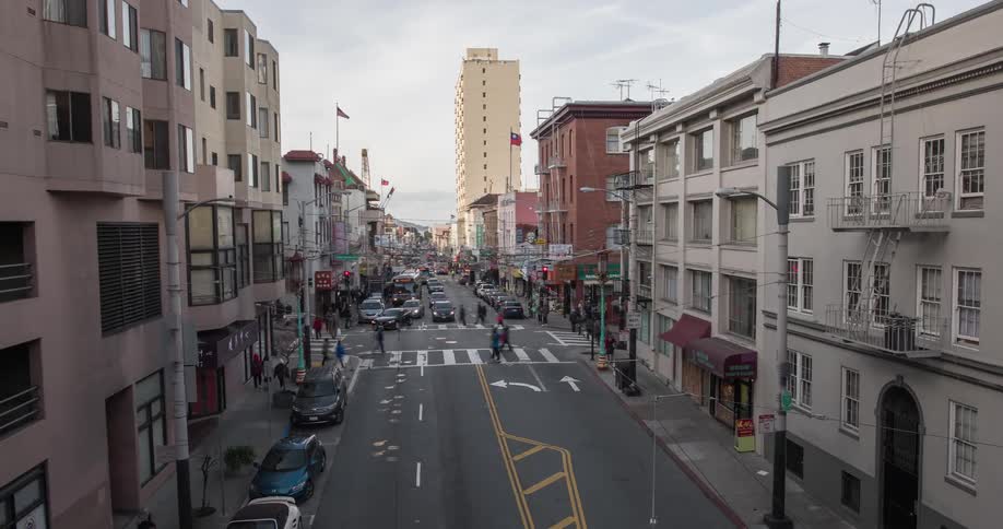 Cars and people travel down a busy city street