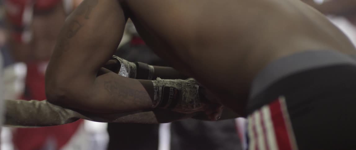 Fighter leans on the ropes watching two others in the ring