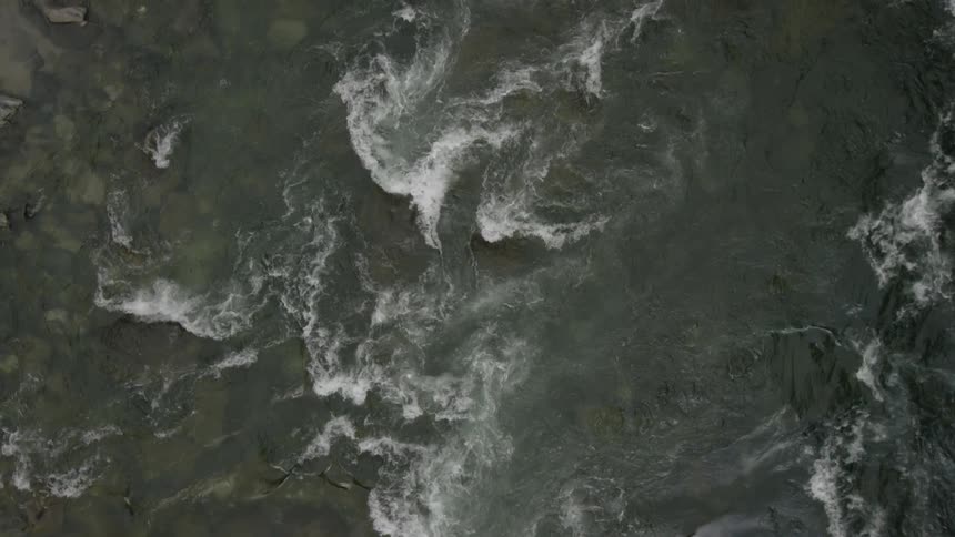 View from above of some rapid waters with rocks underneath