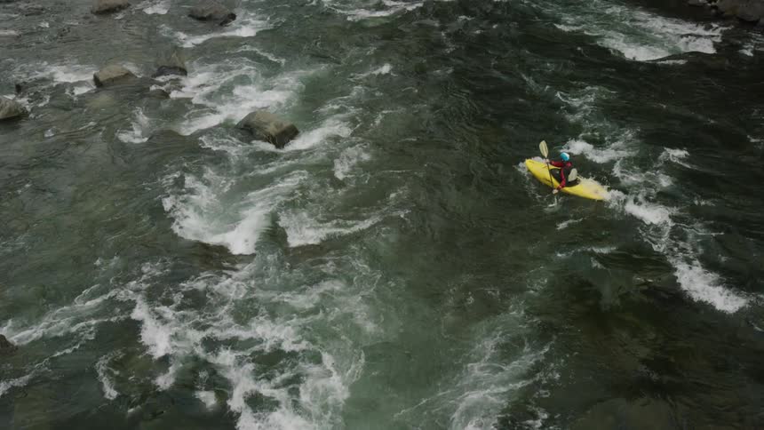 A man rowing down some rapid waters