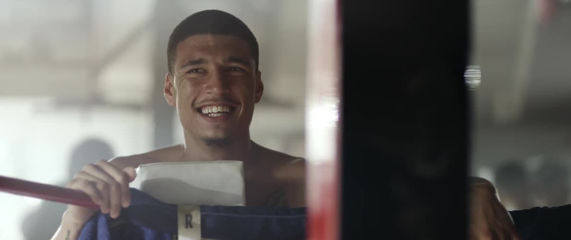 Young man laughs while standing on the apron of a boxing ring
