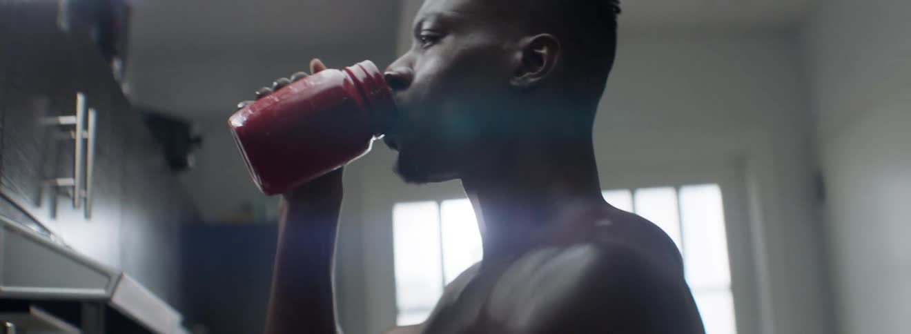 Muscular man drinks a beverage from a jar