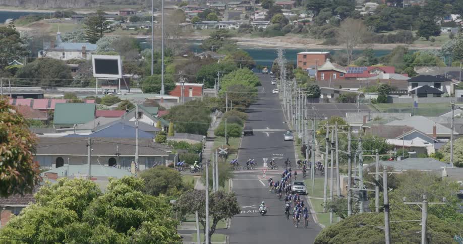 A bike racing peloton is escorted through a town during the day