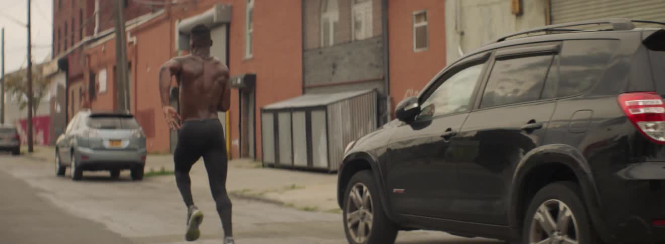 A shirtless man runs down the road