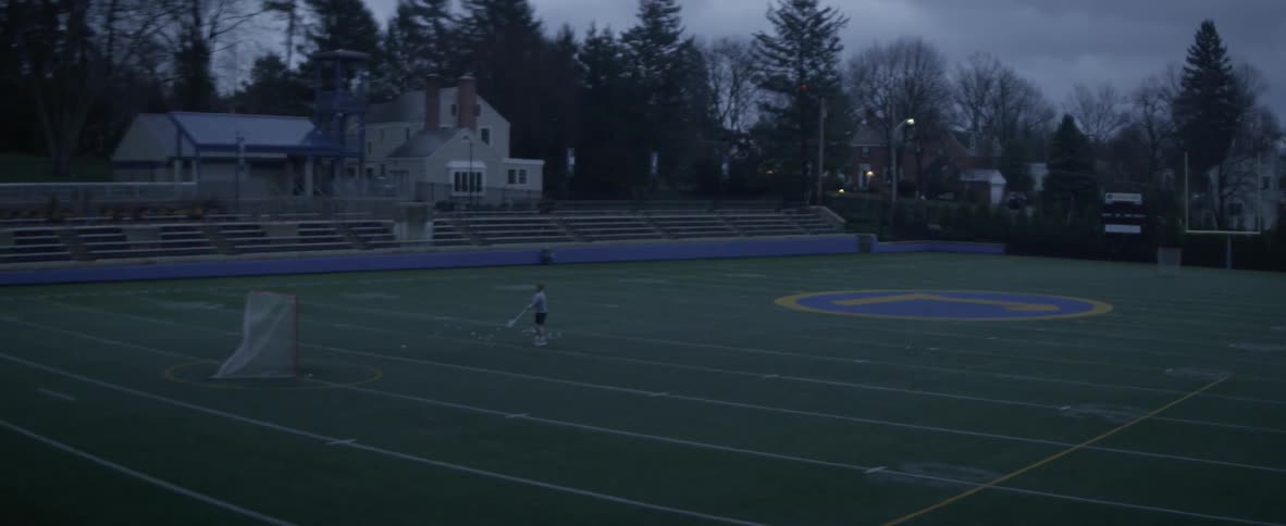 A man plays lacrosse alone on a sports field