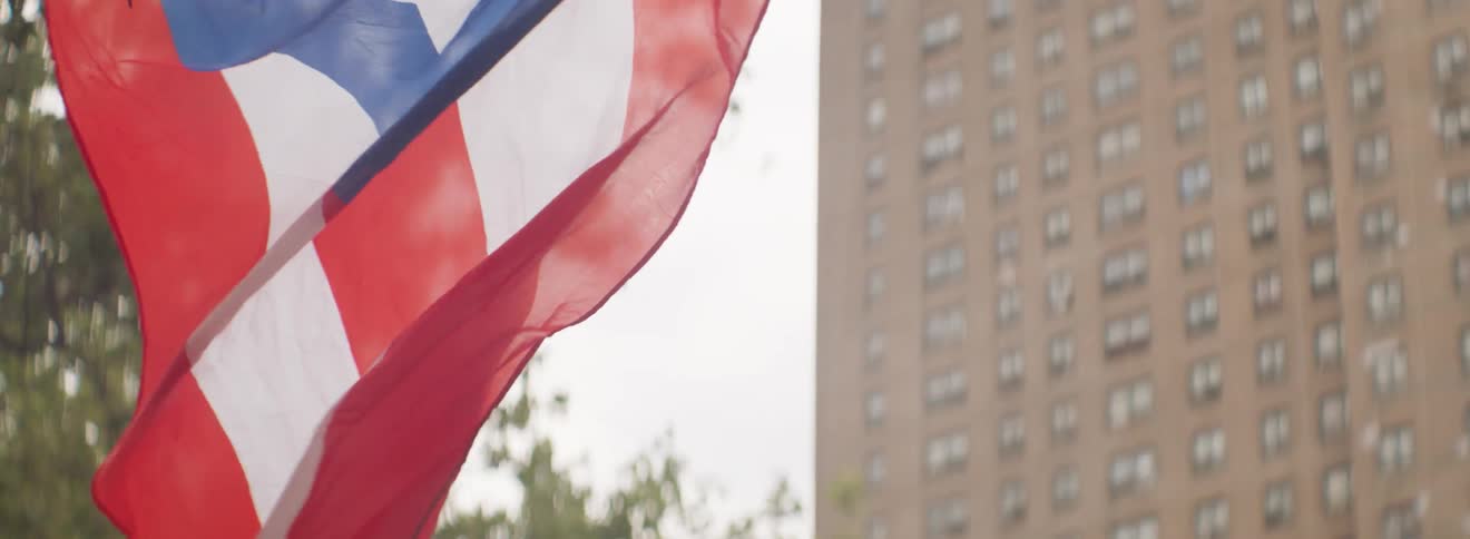 The puerto rican flag blows in the wind outside in a city