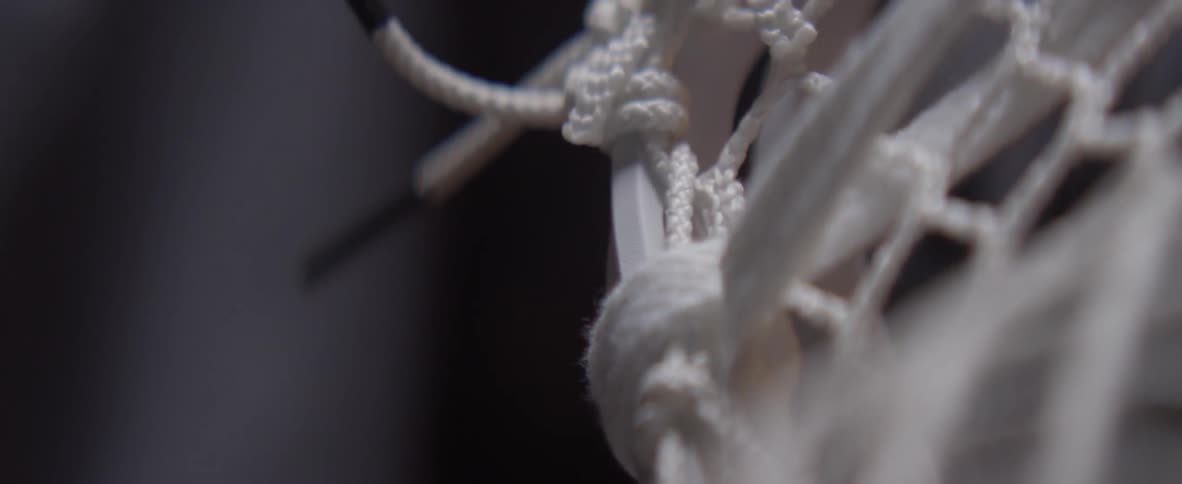 Lacing is being weaved onto a lacrosse stick