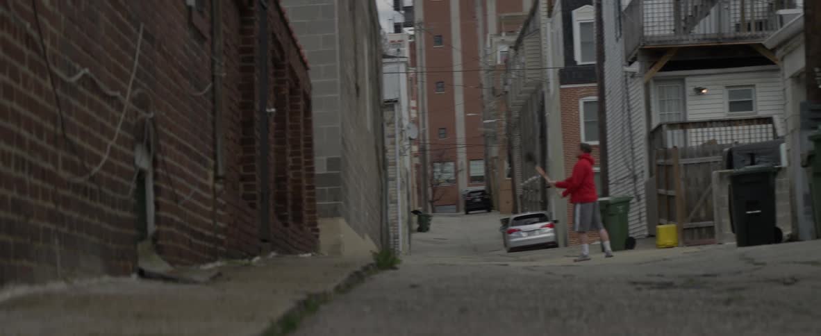 A man is tossing a ball at a wall with a lacrosse stick