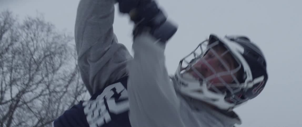 A man plays lacrosse outside while it snows